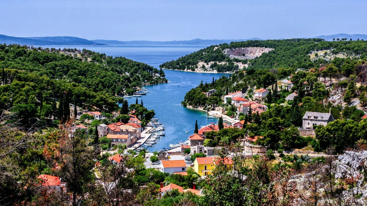 Aerial view of Bobovišća Bay on Brač Island, Croatia, with turquoise waters, stone houses, and yachts anchored along the peaceful coastline.